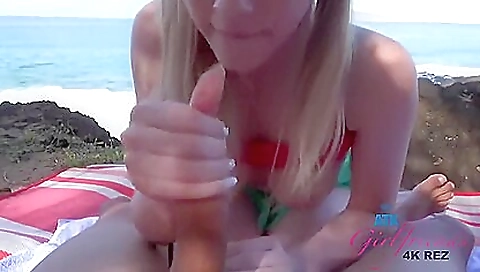 Amateur blonde in swimsuit giving a handjob to a cock